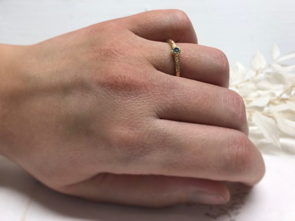 Verlobungsring mit glatter Fassung und blauem Stein Thetes 2 an der linken Hand