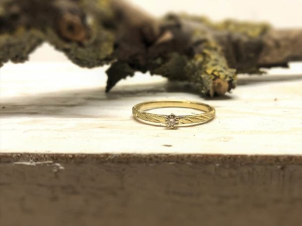 Verlobungsring Vivina aus Gold mit großem Stein, dekoriert auf Holz und Rinde.